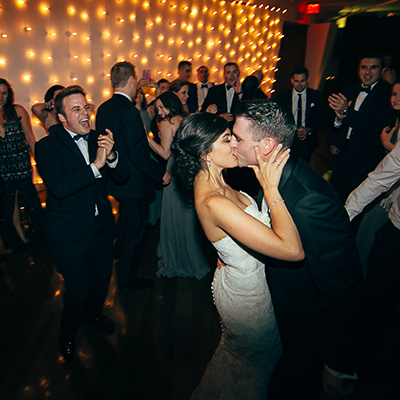 photo: bride and groom kissing on dancefloor while guests applaud