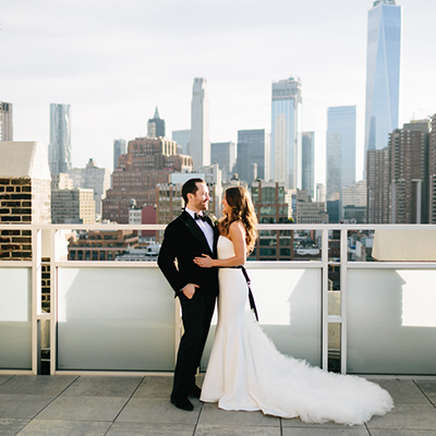 photo: bride and groom laughing on rooftop in daylight overloooking downtown tribeca