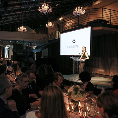 photo: woman presenting on stage at seating corporate dinner
